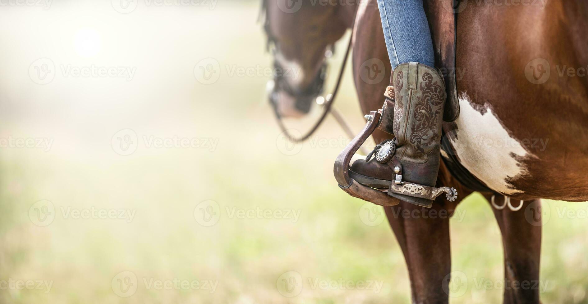 Detail of a ornamented cowboy boots in a stirrup while sitting on a horse photo