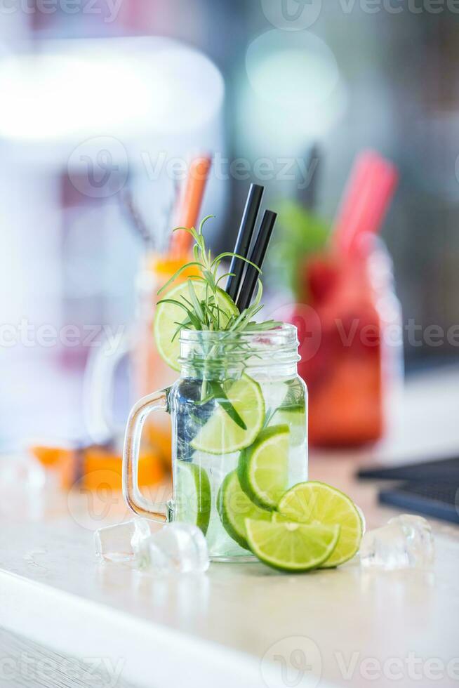 Various lemonades in mason jars with orange lime lemon otange strawberries and fresh fruit fruits photo