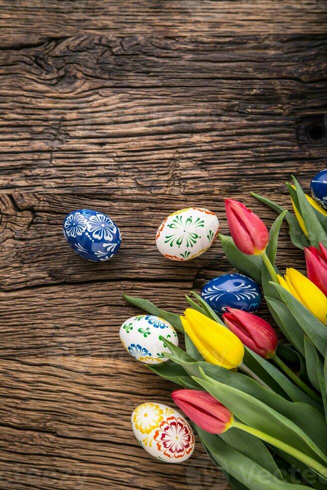 Easter. Hand made easter eggs and spring tulips on old wooden table. photo