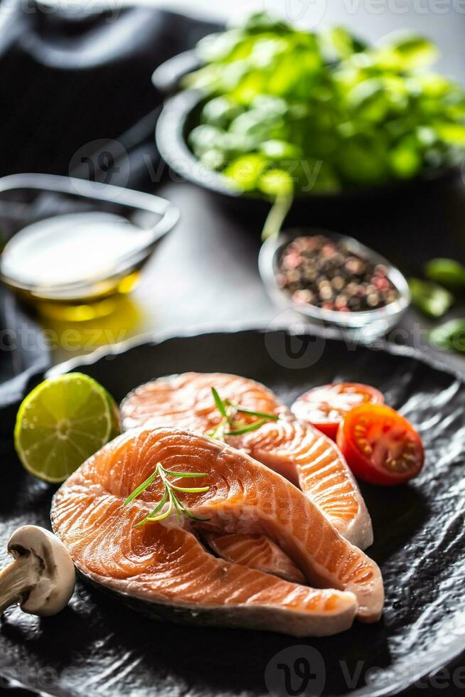 Salmon raw steaks rosemary tomatoes mushroom lime olive oil and spices. photo