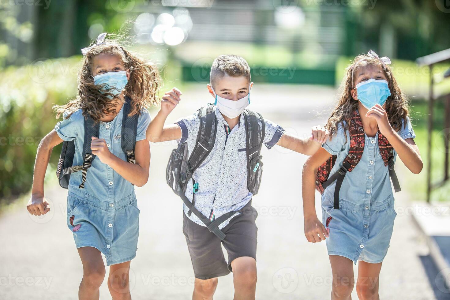 Happy schoolchildren with face masks run from the joy of returning to school during the Covid-19 quarantine photo