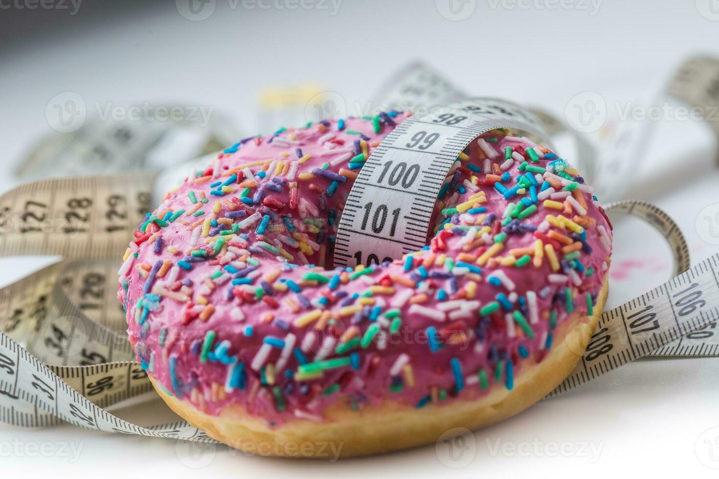 Close-up pink frosted donut with white tailor measure tape photo