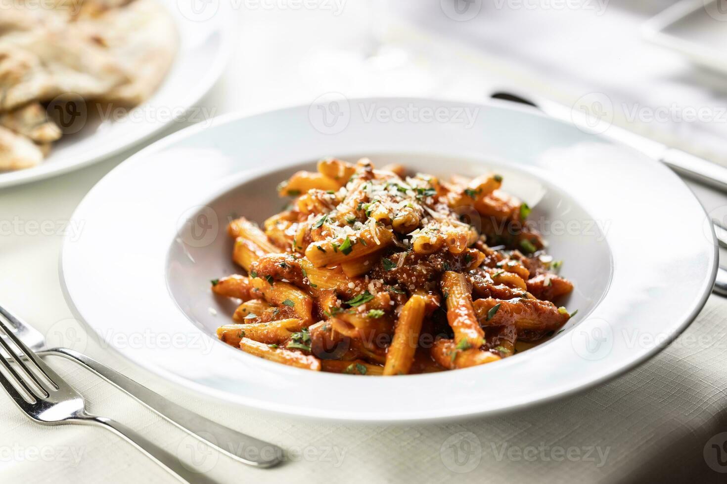 pene alla arrabiata, italiano rojo salsa pasta servido en un mesa en un plato con Fresco rejilla de parmesano foto