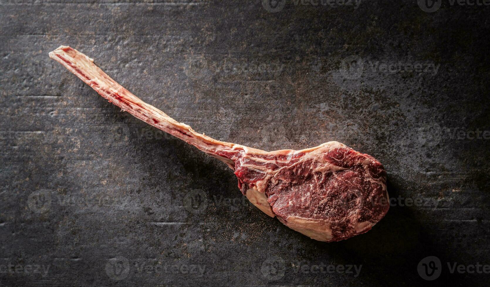 Raw tomahawk steak on a old rustic board - Top of view. photo