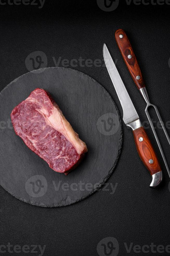 Fresh raw beef striploin steak with salt, spices and herbs photo