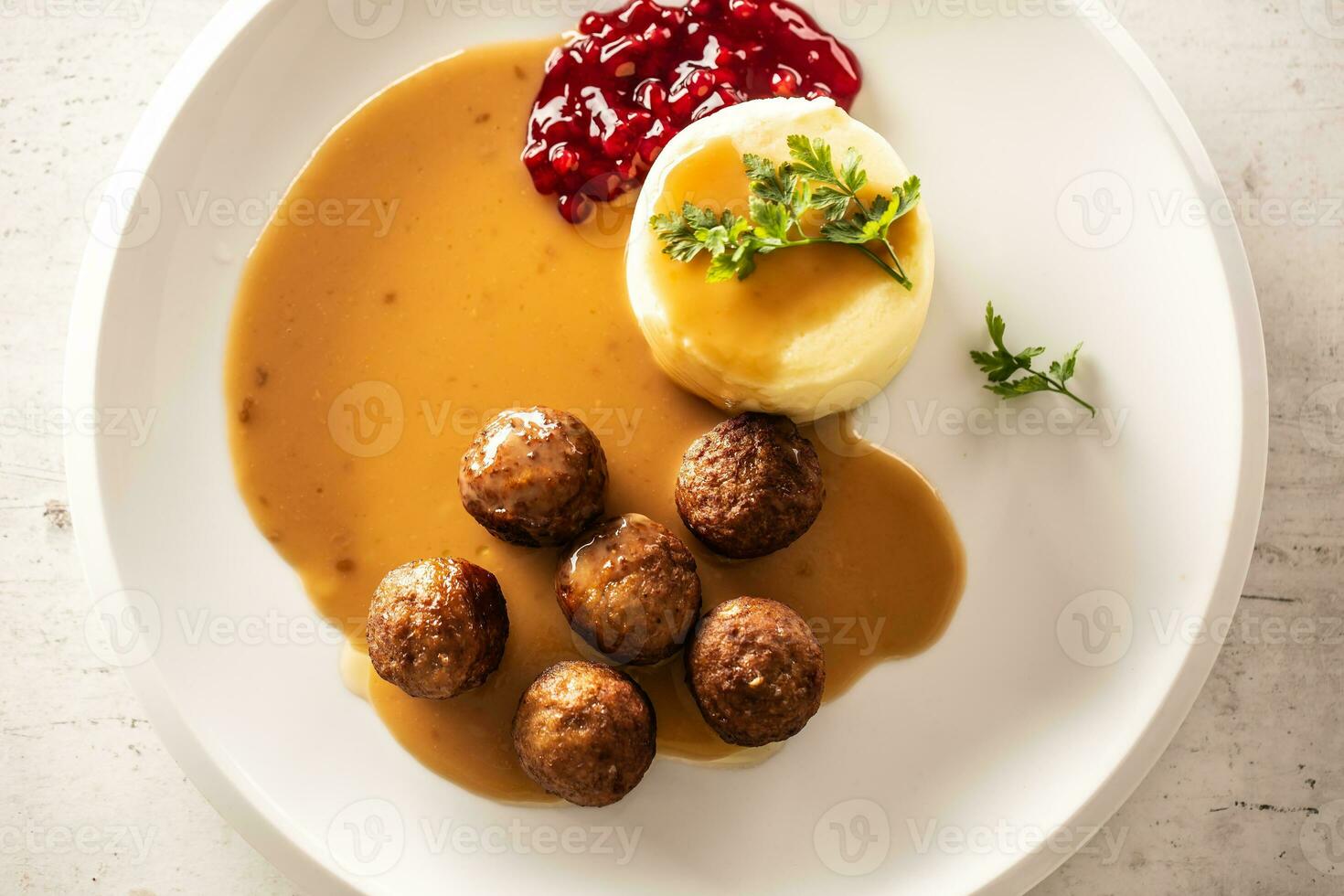 Top view of a plate with Swedish meatballs in sauce with mashed potatoes and cranberry sauce photo