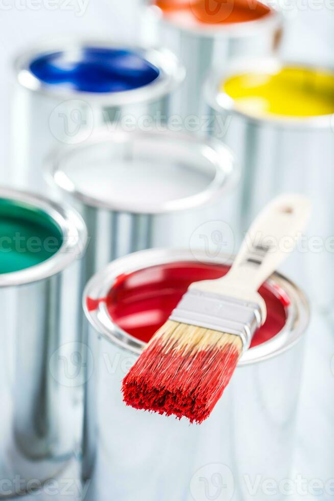 Close-up brush with red color lying on paint can. photo