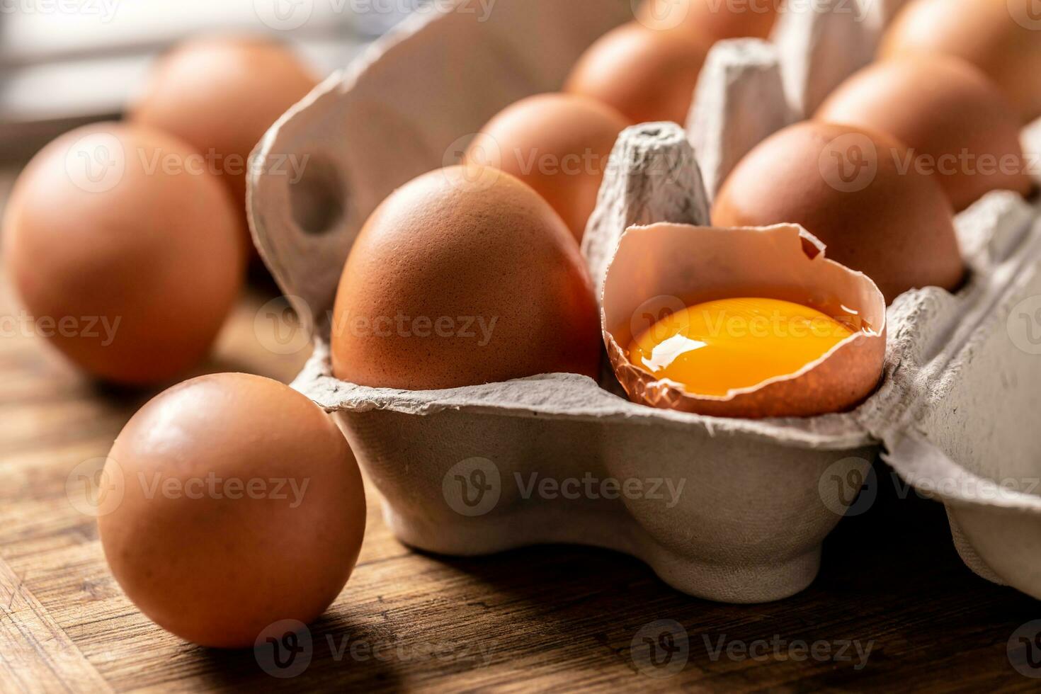 Close-up of a broken egg with a yolk in a cardboard box photo
