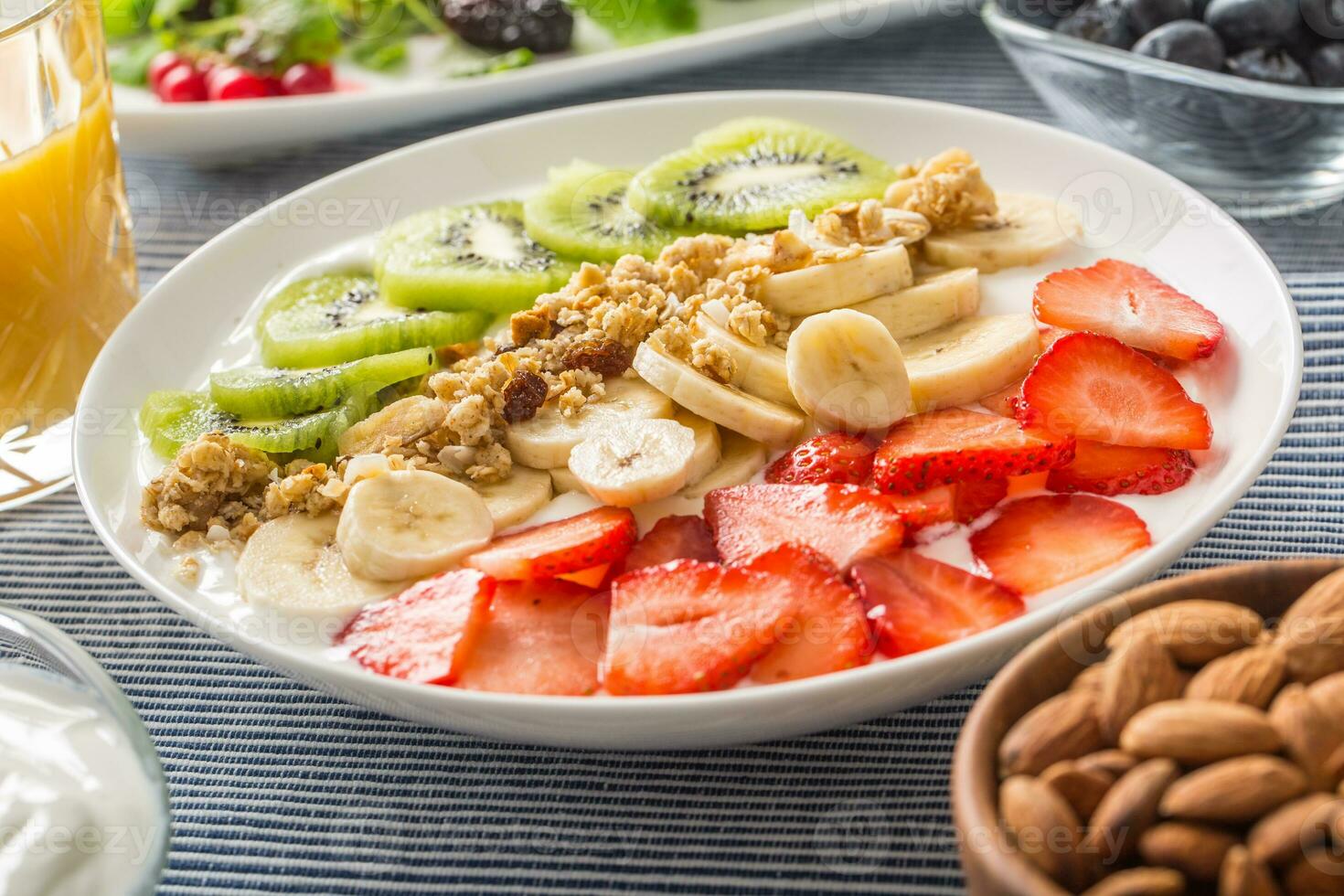 Healthy breakfast served with plate of yogurt muesli kiwi strawberries and banana photo