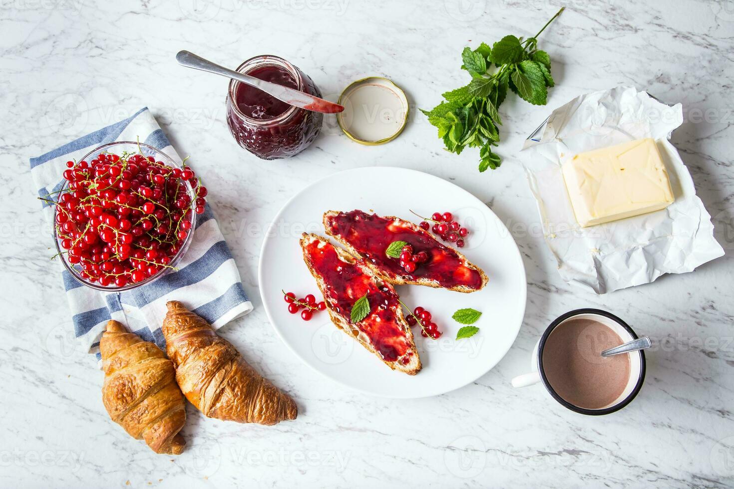 Tasty breakfast with red currants marmalade croissants butter and mint leaves photo