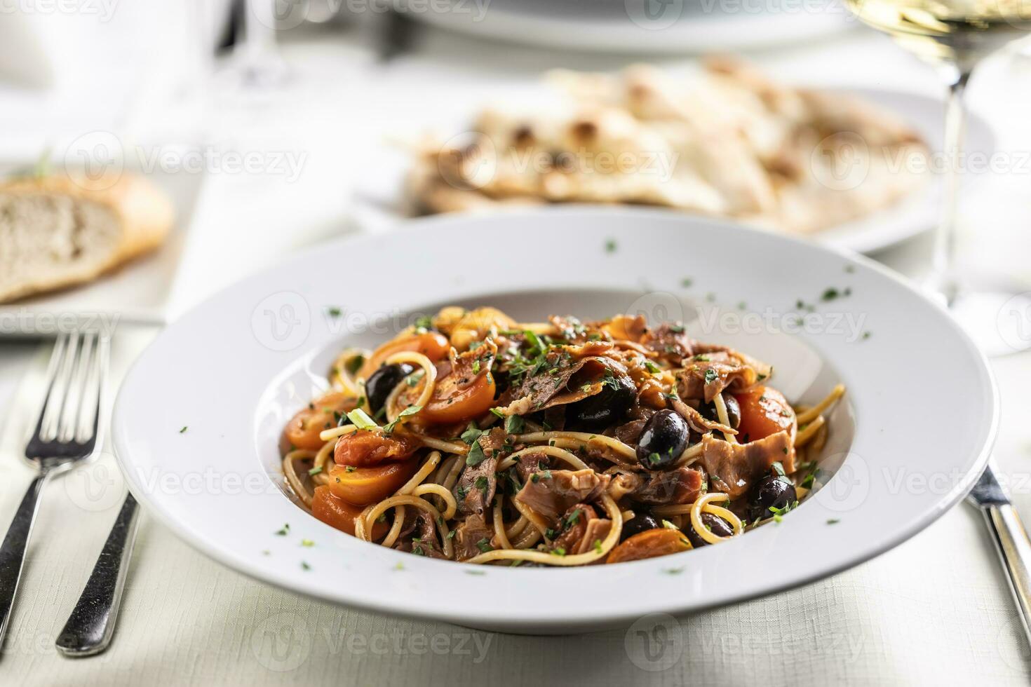 toda amatriciana pasta con Tomates, aceitunas y panceta en un plato foto