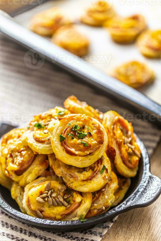 Rolls of puff pastry with ham bacon cheese sesame in dish photo