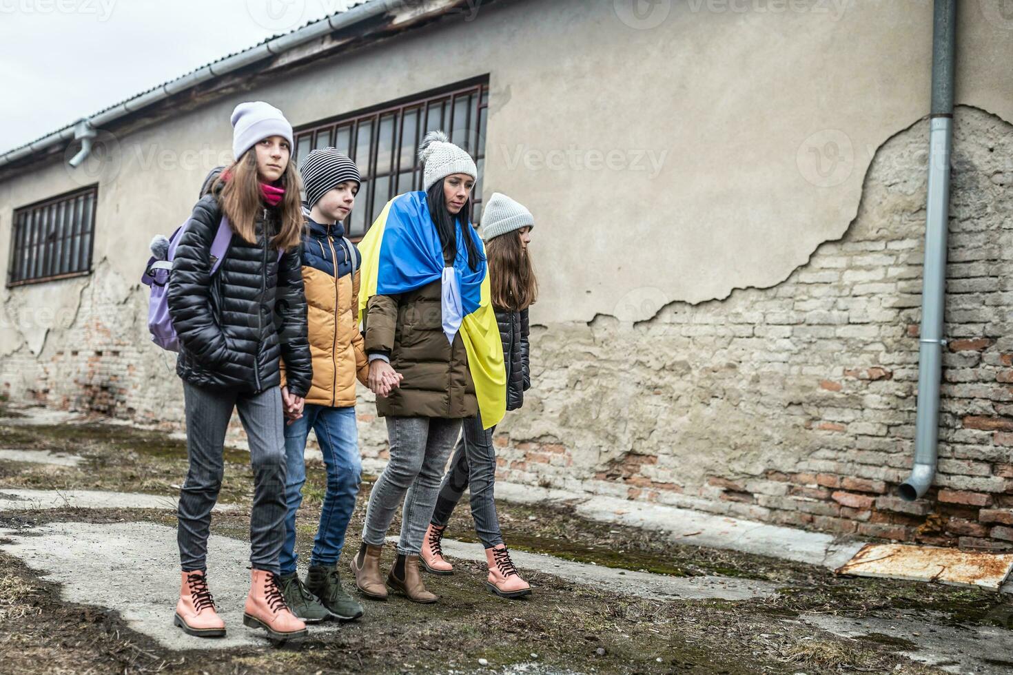 Vysne Nemecke, Slovakia. March 09. 2022. Woman holds Ukrainian flag as she flees the conflict with Russia with three kids in a derelict surroundings photo