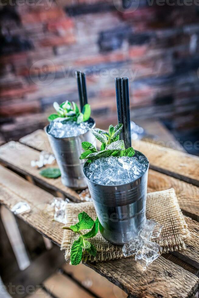 Mint julep cocktail alcoholic drink on wooden board in pub or restaurant photo