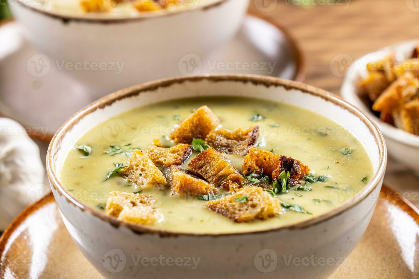 Garlic cream soup with bread croutons in rustic bowl - Close up photo