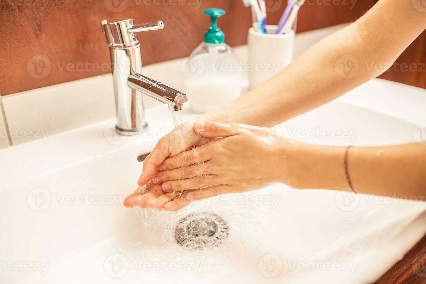 Washing hands with water and liquid soap in the bathroom photo