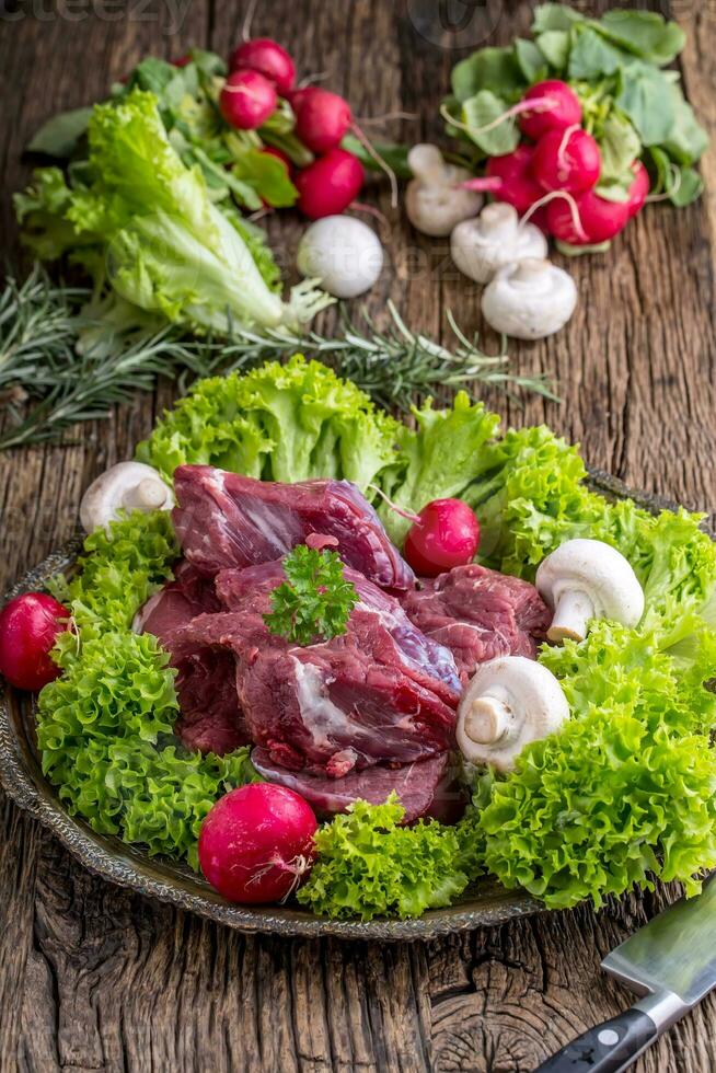 crudo carne de vaca carne con Fresco vegetal. rebanado carne de vaca filete en lechuga ensaladas rábanos y hongos. foto
