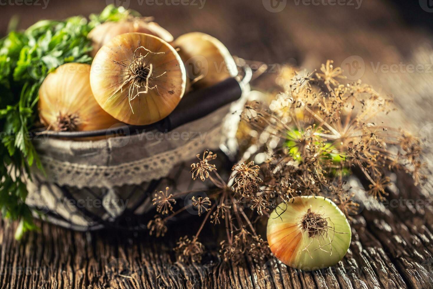 Bundle of freely lying dried onion with parsley herbs and dill in basket on a wooden table photo