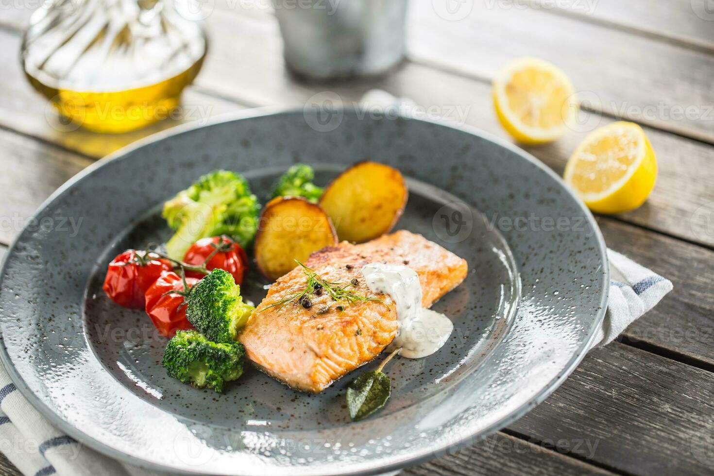 Roasted salmon fillet broccoli tomatoes and fried potatoes with dill cream sauce photo