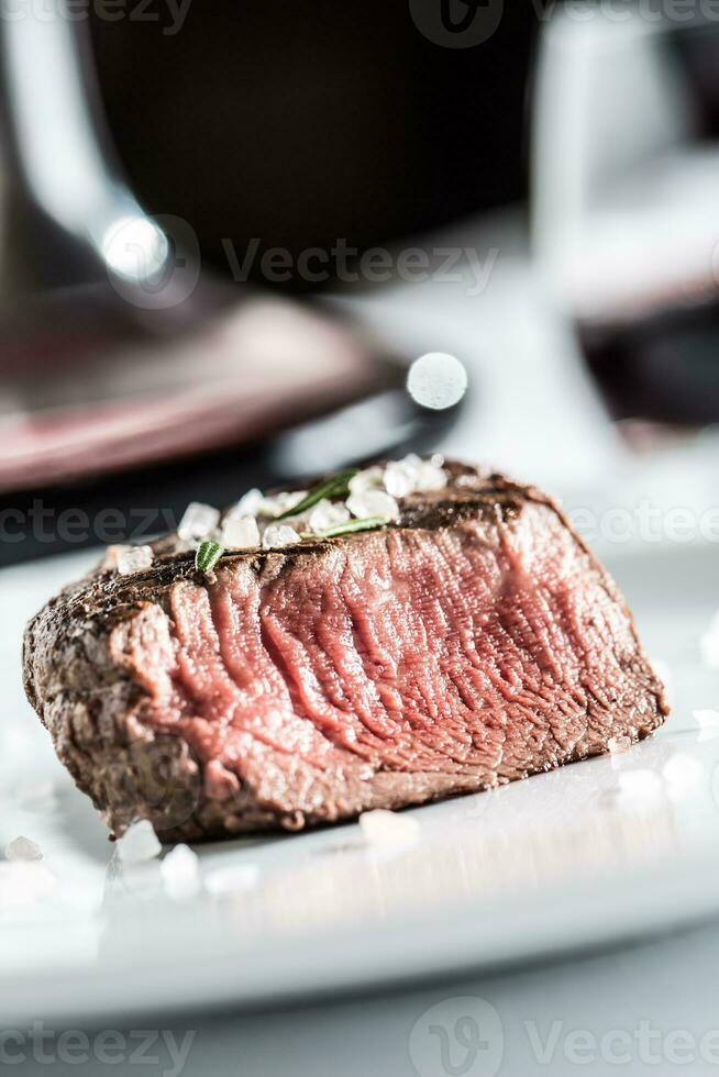 Beef tenderloin steak on white plate and red wine in pub or restaurant photo