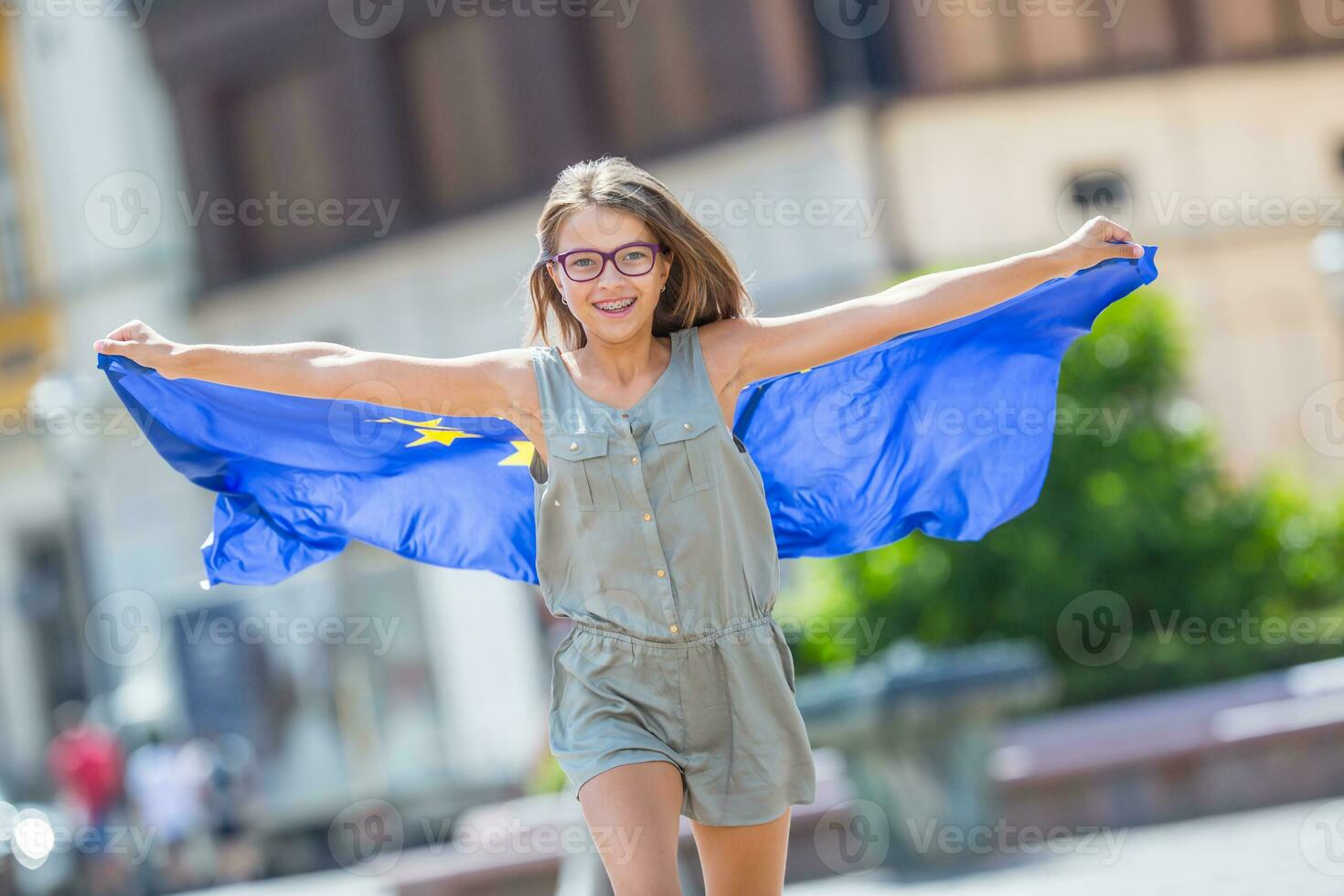 EU Flag. Cute happy girl with the flag of the European Union. Young teenage girl waving with the European Union flag in the city photo