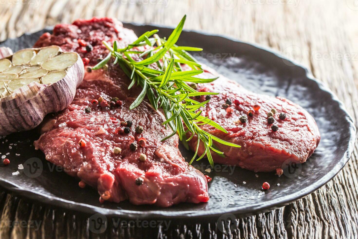 Beef meeat Rib-Eye steak wit rosemary salt and pepper on black plate photo