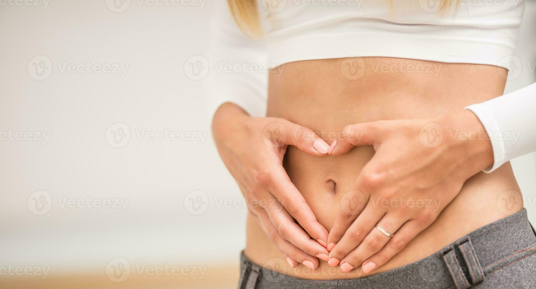 woman with sports figure on her belly shows heart shape photo
