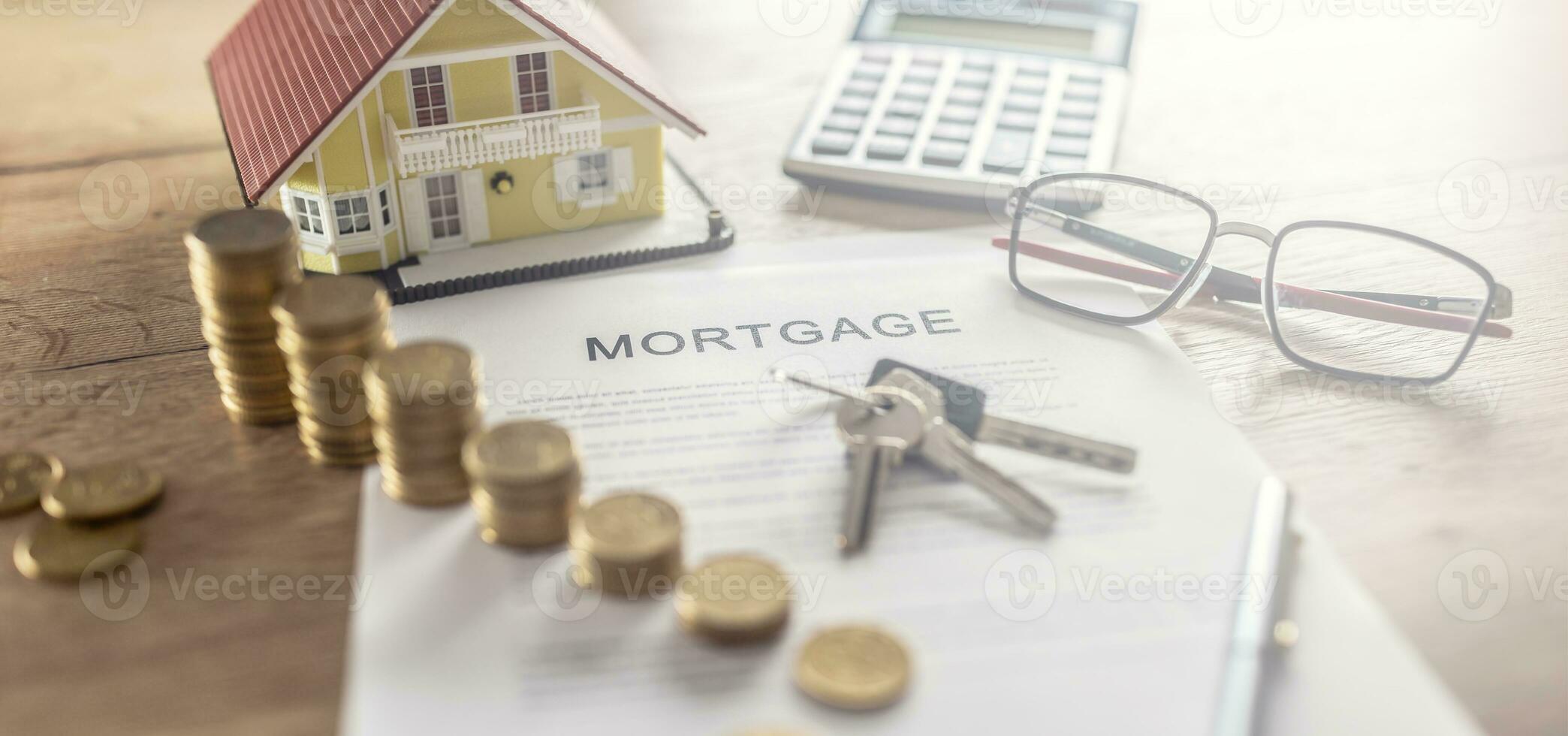 Mortgage contract for the purchase or sale of an apartment house or real estate. Work desk with contract coins model house calculator and pen photo