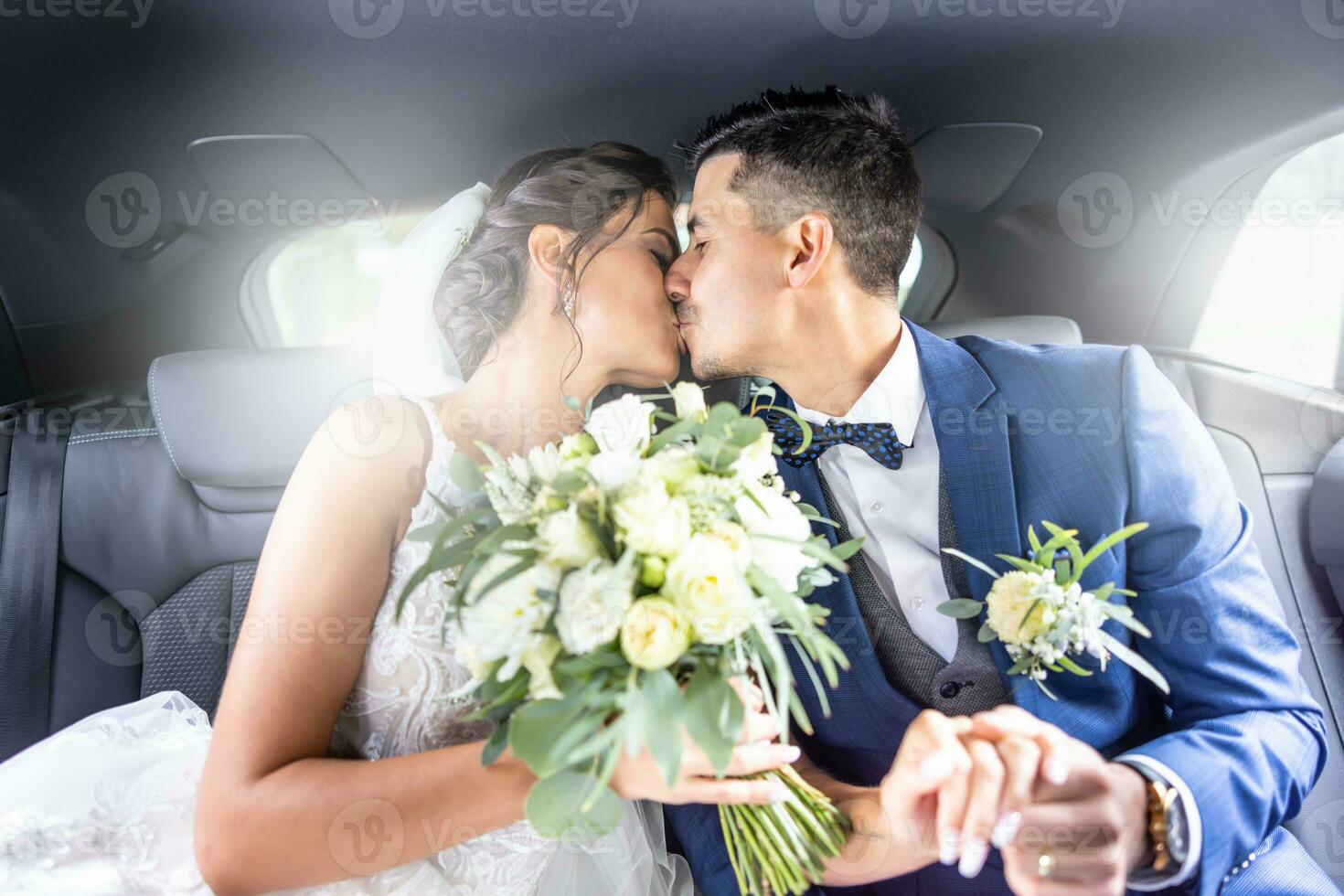 contento joven sólo casado Pareja Besos en el coche participación manos y novia participación un Boda ramo de flores foto