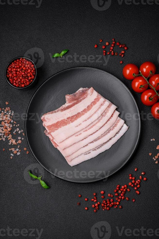 Fresh raw bacon cut into slices with salt, spices and herbs photo