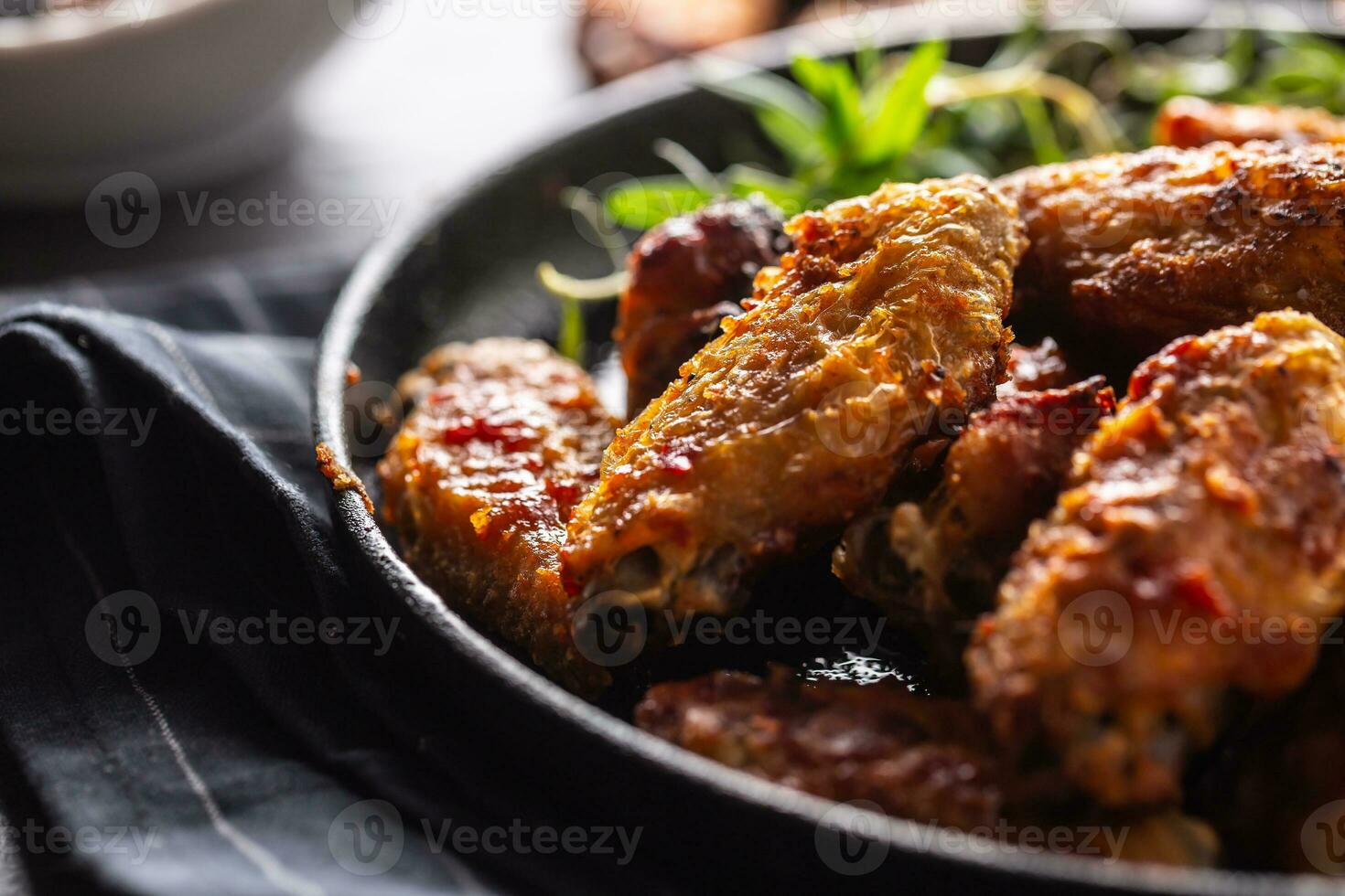 pollo alas parrilla en un emitir hierro horneando plato con barbacoa salsa y Romero foto