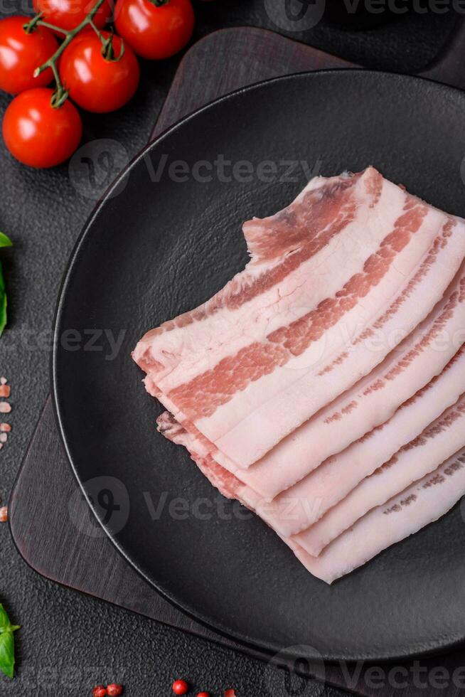 Fresh raw bacon cut into slices with salt, spices and herbs photo