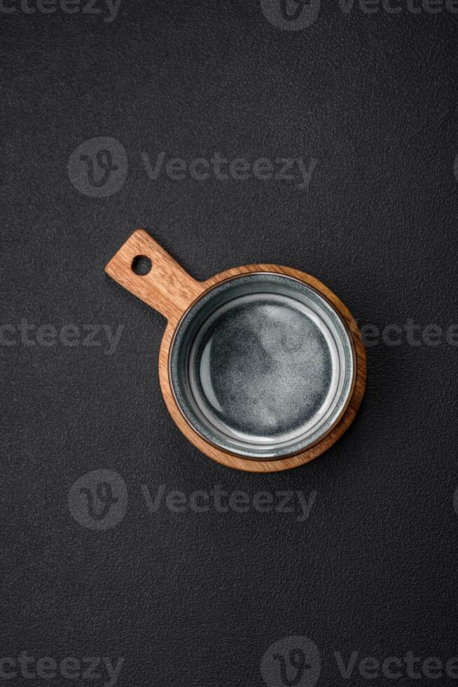 Empty round ceramic bowl on a wooden cutting board in brown color photo