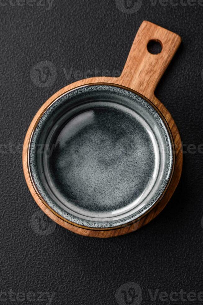 Empty round ceramic bowl on a wooden cutting board in brown color photo
