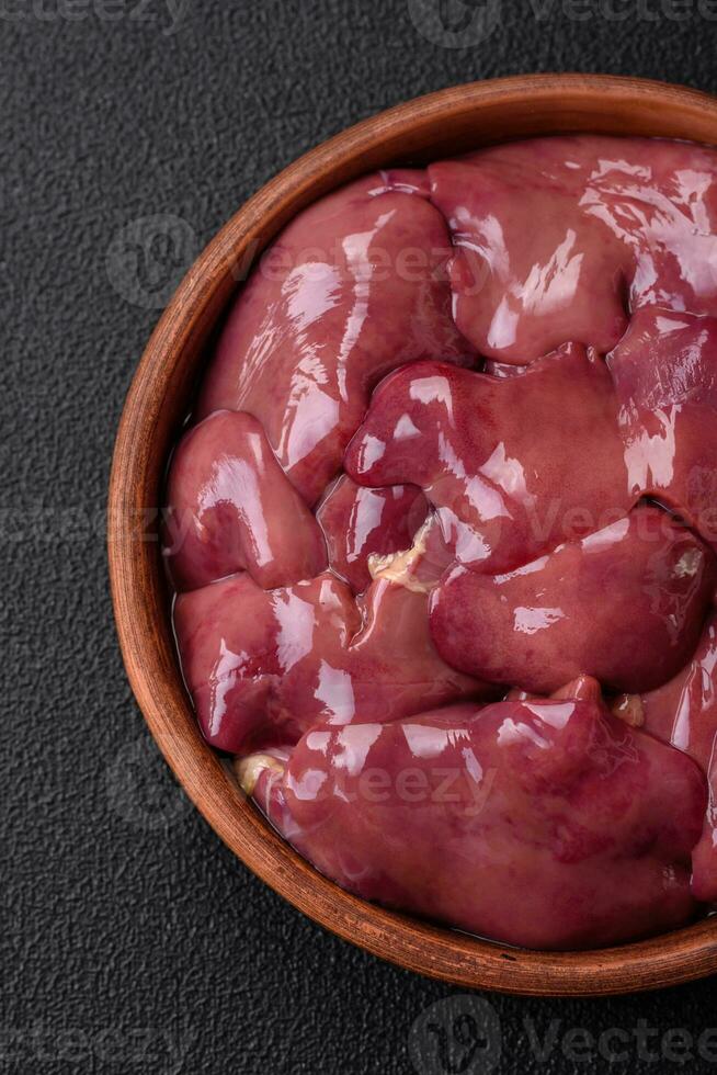 Fresh raw chicken or turkey liver in a ceramic plate with salt, spices and herbs photo