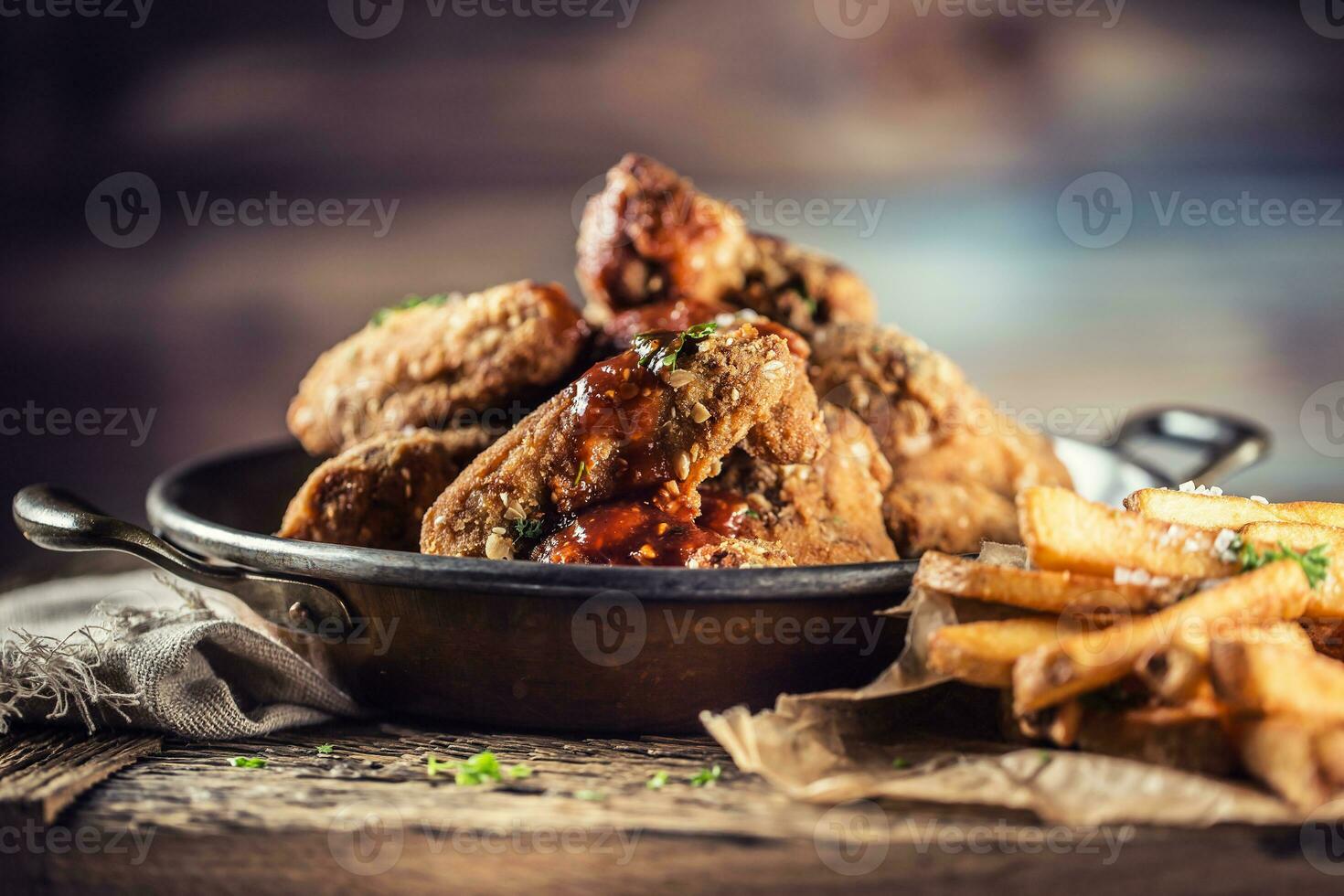 Fried chicken wings with fries on table in pub. photo