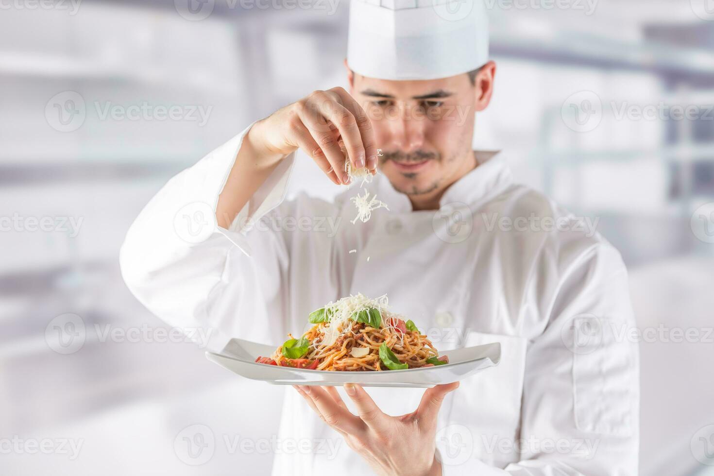 Chef in restaurant kitchen prepares and decorates meal with hands.Cook preparing spaghetti bolognese photo