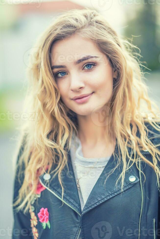 Portrait of attractive blonde girl with curly long hair and blue eyes photo