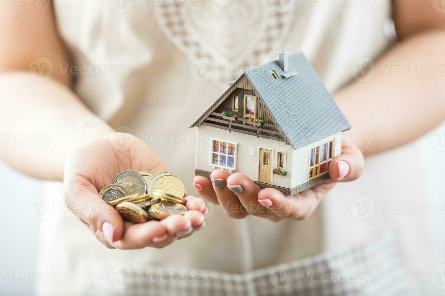 Hands of young hosewife holding model house and euro coins photo