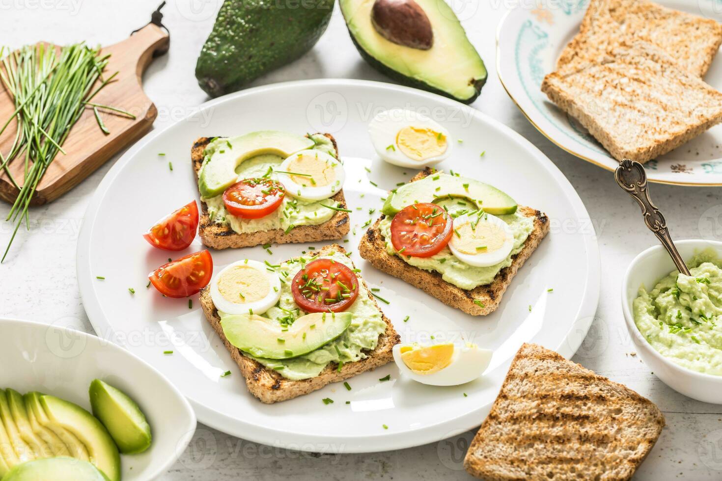 Healthy breakfast from toasts with avocado spread guacamole egg tomato and chives. photo