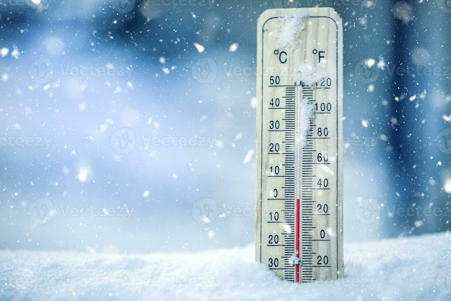 Thermometer on snow shows low temperatures - zero. Low temperatures in degrees Celsius and fahrenheit. Cold winter weather - zero celsius thirtytwo farenheit. photo