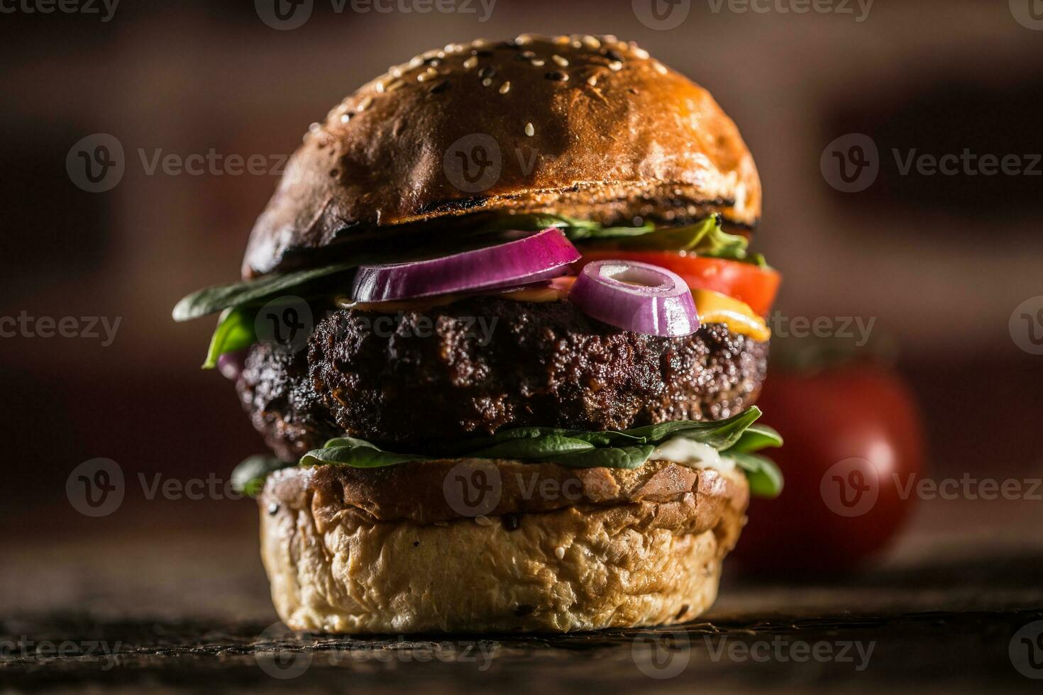 Tasty beef burger with spinach leaves salad onion tomato and cheese photo