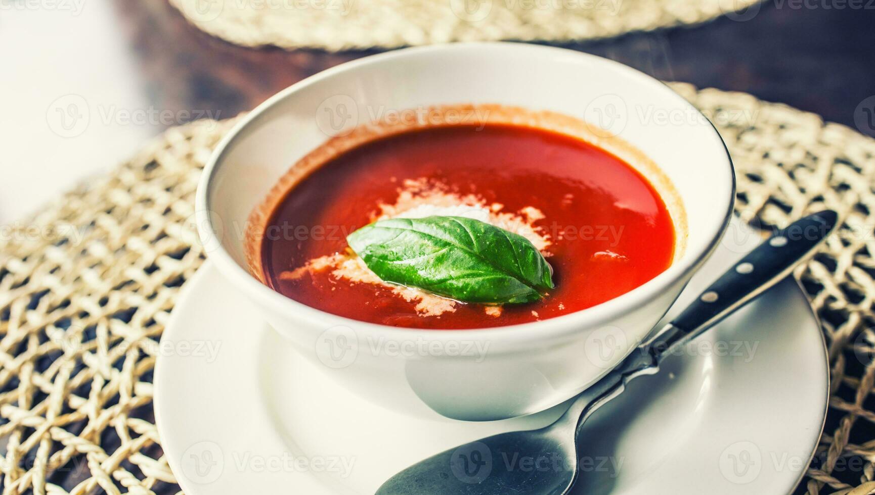 Tomato soup with parmesan cheese and basil leave. photo