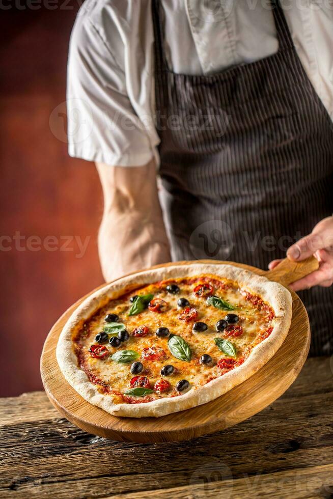 cocinero y Pizza. cocinero ofrecimiento Pizza en hotel o restaurante foto