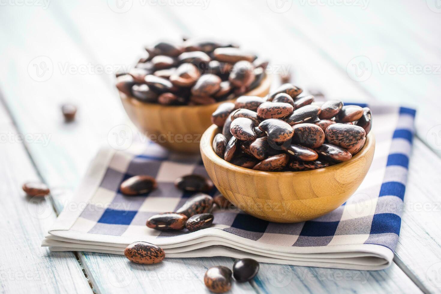 Uncooked beans in wooden bowles on kitchen table. photo