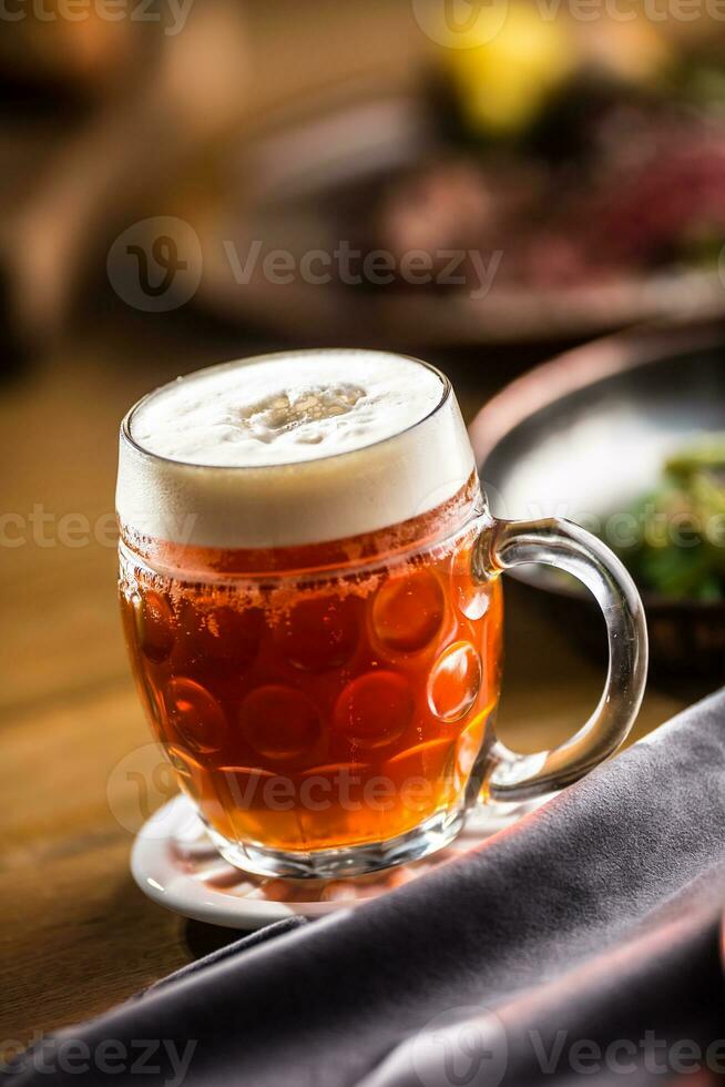 Draft beer with foam on bar counter in pub. photo