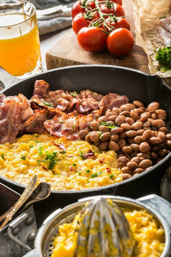 Full table of english breakfast. Scrambled eggs grilled bacon beans toast bread orange juice and coffee photo