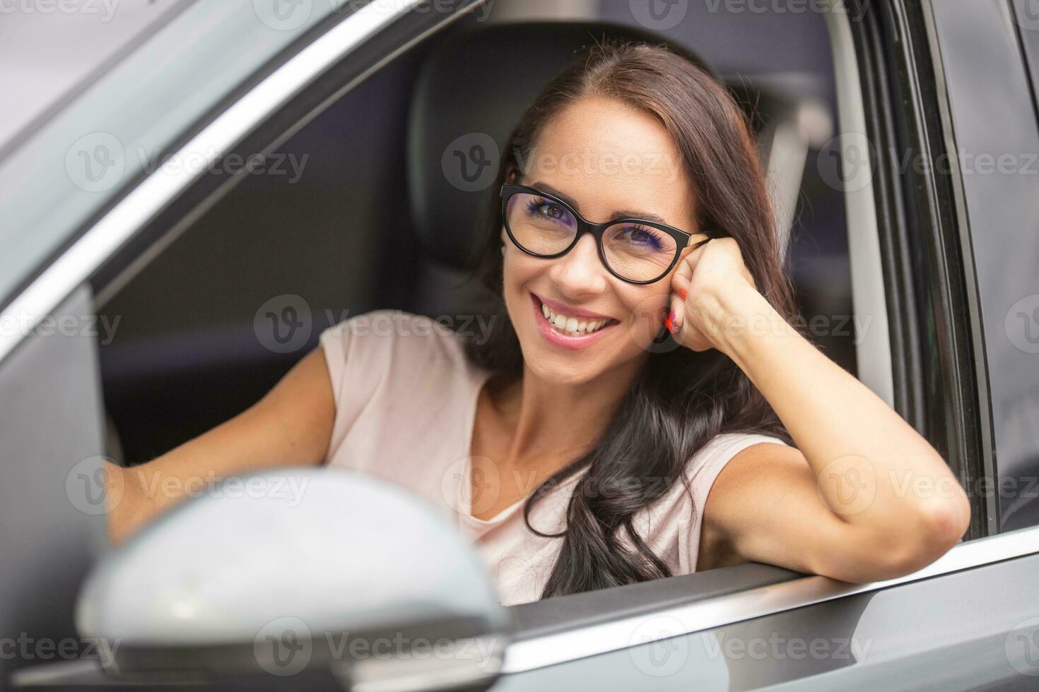 Smiling with glasses drives a car, with one arm out of the