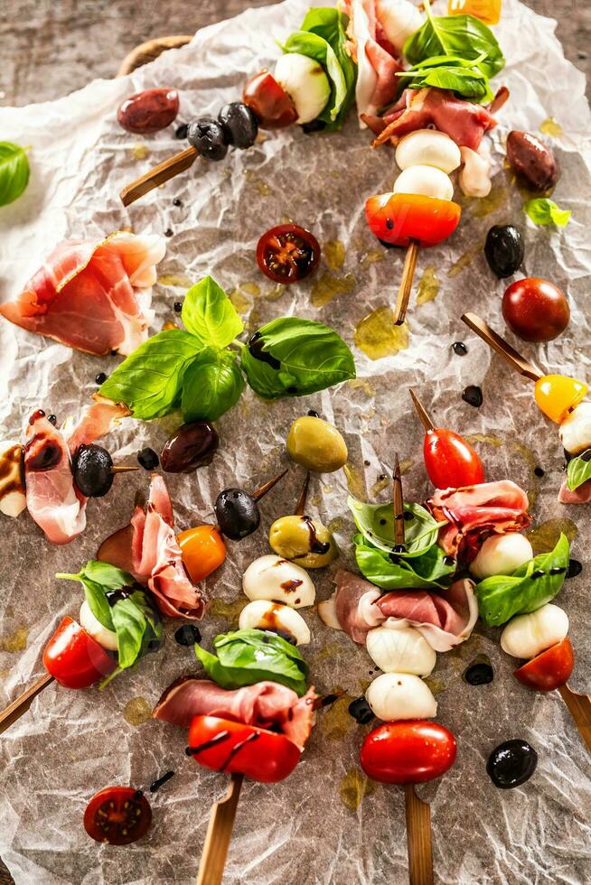 Caprese skewers italian or mediterranean appettizer tomatoes mozzarella olives and prosciutto photo