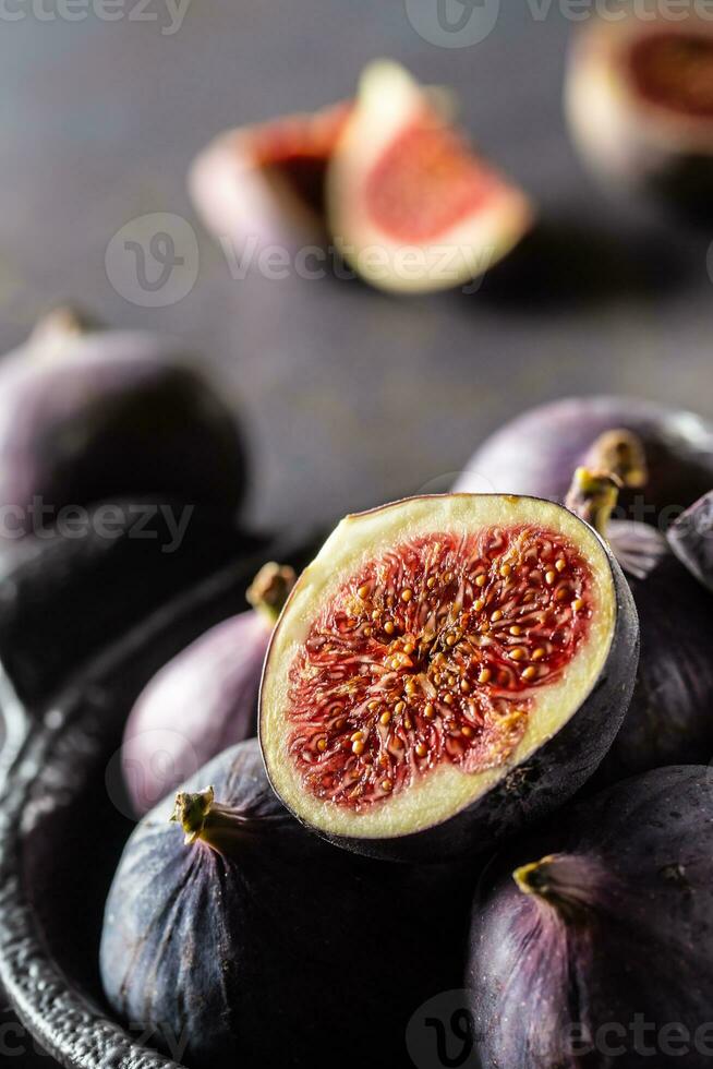 A few figs in a black bowl on an dark concrete table photo